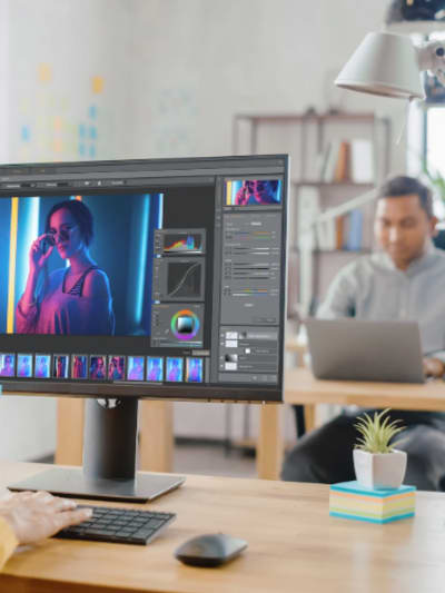 Graphic designer works on a computer in an open office setting.